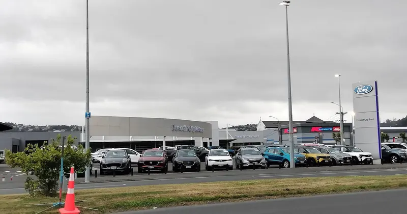 Coches nuevos y seminuevos alineados en la explanada de un concesionario bajo un cielo nublado